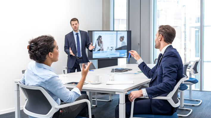 Future of Work @ BASF – Zwei Männer und eine Frau zeigen in Richtung eines Bildschirms (Foto)